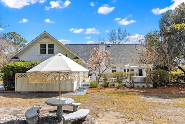 rear view of house featuring a shingled roof and a chimney