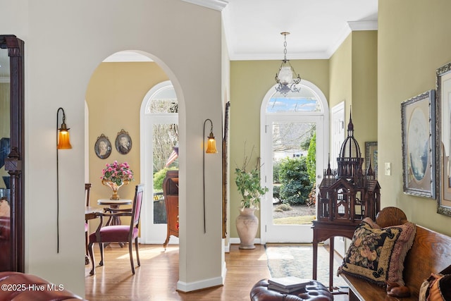 entryway featuring arched walkways, crown molding, baseboards, and wood finished floors