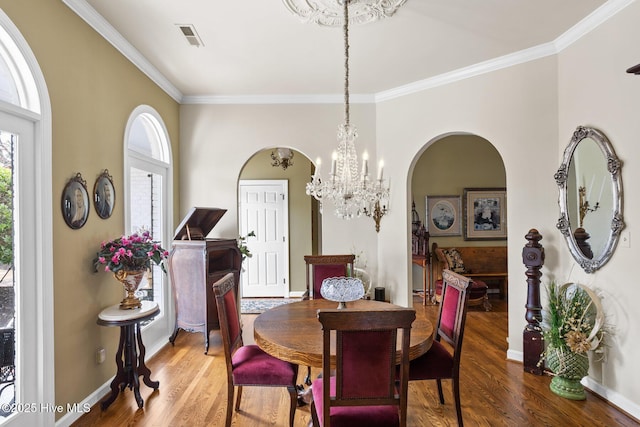 dining area featuring arched walkways, visible vents, ornamental molding, and wood finished floors