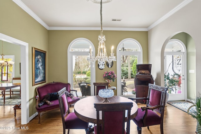 dining area with an inviting chandelier, wood finished floors, baseboards, and ornamental molding