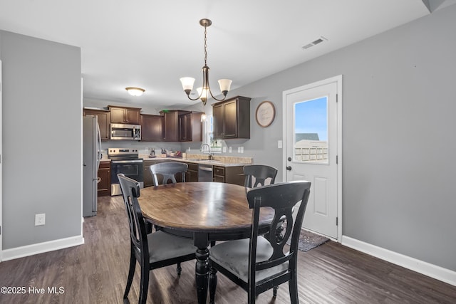 dining area featuring baseboards, visible vents, a notable chandelier, and wood finished floors