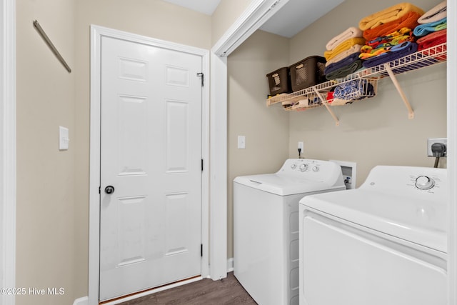 clothes washing area with dark wood-type flooring, separate washer and dryer, and laundry area