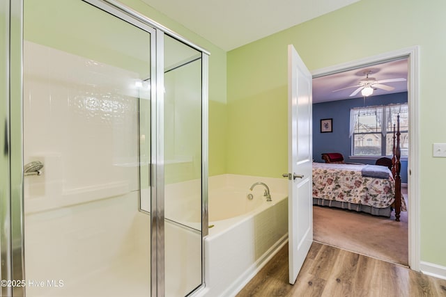 ensuite bathroom with a ceiling fan, wood finished floors, ensuite bathroom, a shower stall, and a bath