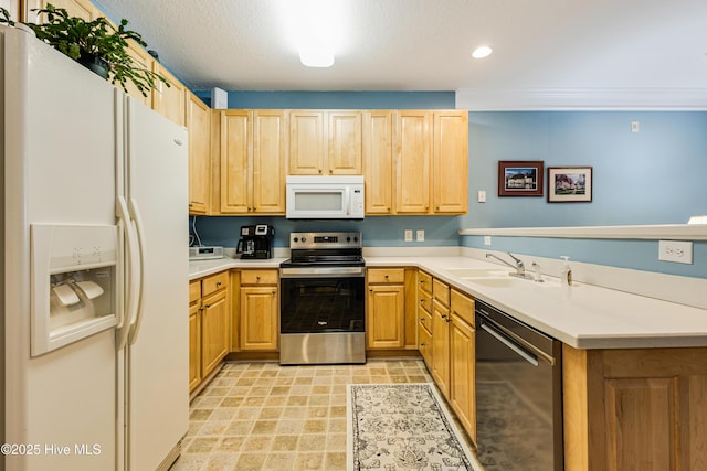 kitchen featuring a peninsula, stainless steel appliances, light countertops, light brown cabinets, and a sink