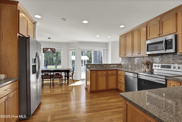 kitchen featuring a sink, tasteful backsplash, appliances with stainless steel finishes, and light wood-style flooring