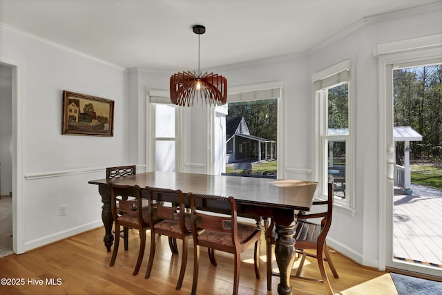 dining space with light wood-type flooring, baseboards, and ornamental molding