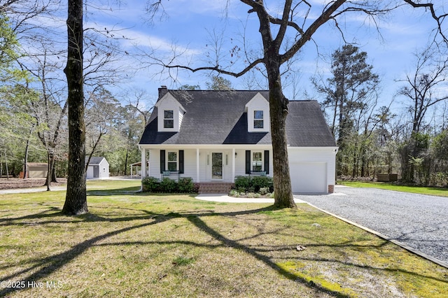 new england style home featuring driveway, an attached garage, covered porch, a chimney, and a front lawn