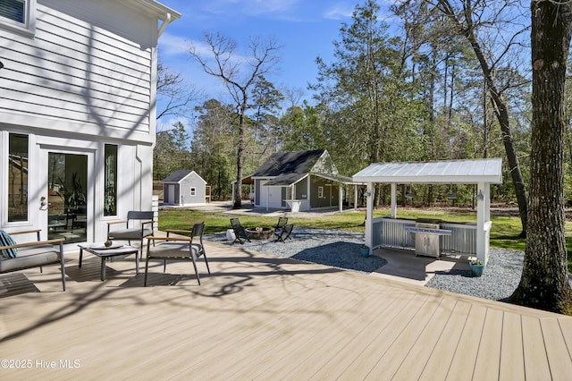 wooden terrace featuring an outdoor structure and an outdoor fire pit