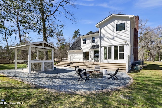 rear view of house featuring a patio area, a lawn, a chimney, and a fire pit