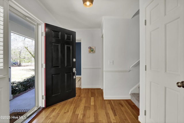 entrance foyer featuring stairs, crown molding, light wood-style flooring, and baseboards