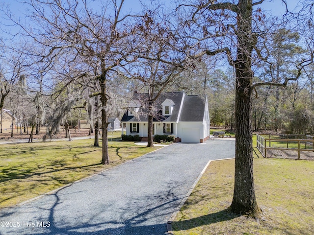 new england style home featuring driveway, a front lawn, and fence