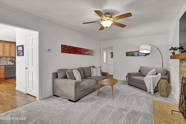 living area featuring a fireplace, baseboards, crown molding, and a ceiling fan