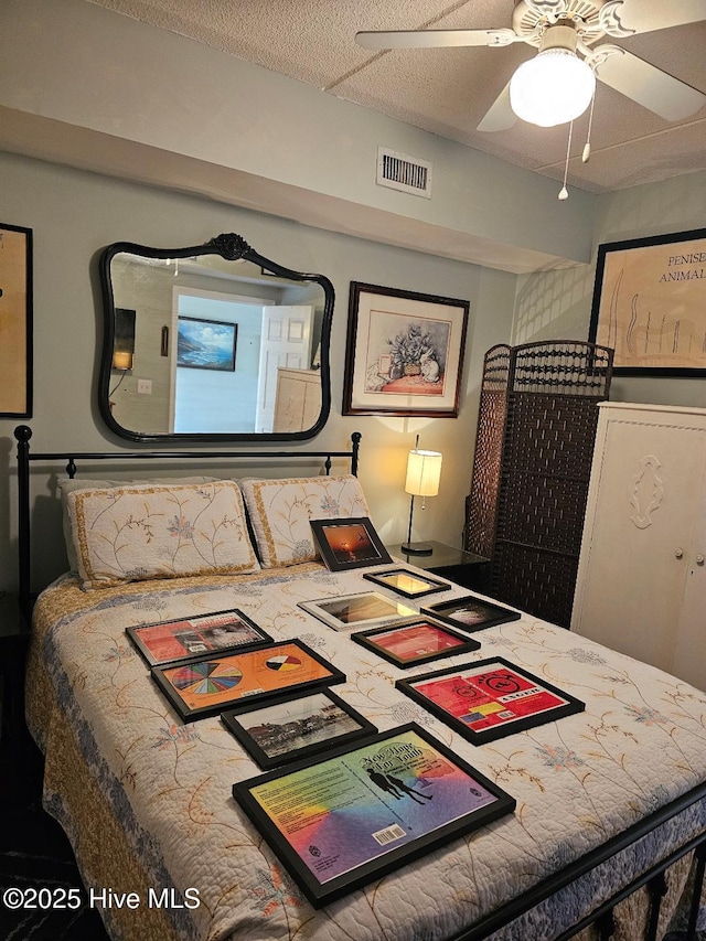 bedroom with a textured ceiling, visible vents, and a ceiling fan