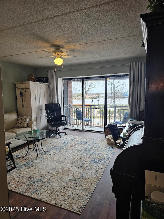 living area featuring a textured ceiling, ceiling fan, plenty of natural light, and wood finished floors