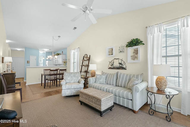 living area featuring lofted ceiling, ceiling fan with notable chandelier, and a wealth of natural light