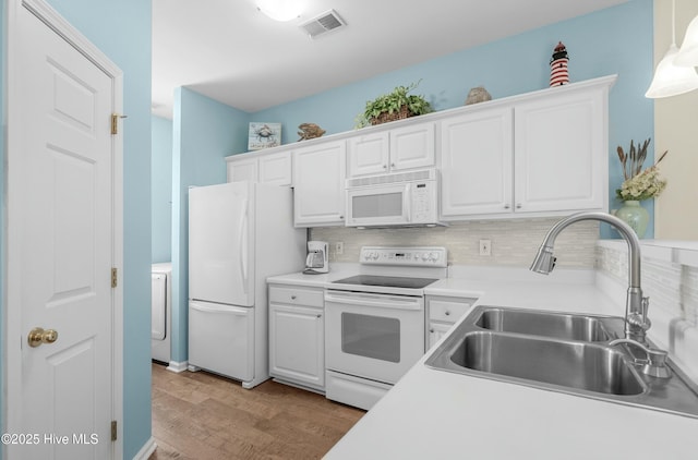 kitchen featuring white appliances, white cabinetry, visible vents, and a sink