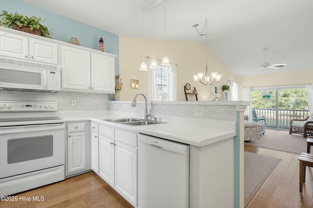 kitchen with a peninsula, white appliances, a sink, and a wealth of natural light