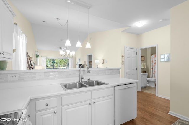 kitchen with lofted ceiling, white dishwasher, light countertops, white cabinetry, and a sink