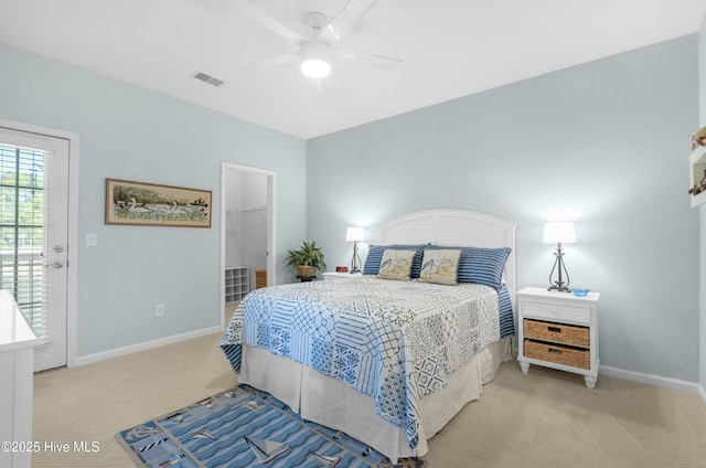 carpeted bedroom featuring baseboards, a spacious closet, visible vents, and ceiling fan