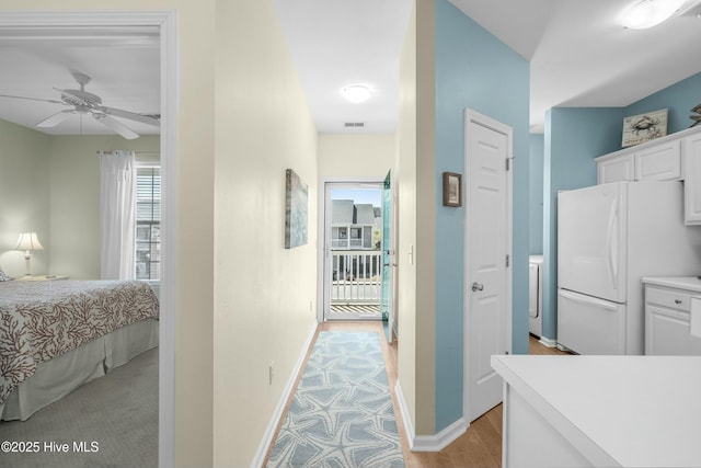 corridor featuring light wood finished floors, visible vents, and baseboards