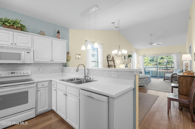 kitchen with white appliances, dark wood finished floors, open floor plan, a peninsula, and a sink