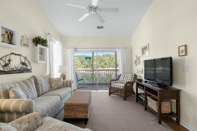 living room with a ceiling fan, visible vents, vaulted ceiling, and baseboards