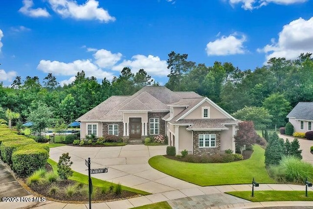 view of front of home with driveway, stone siding, and a front yard