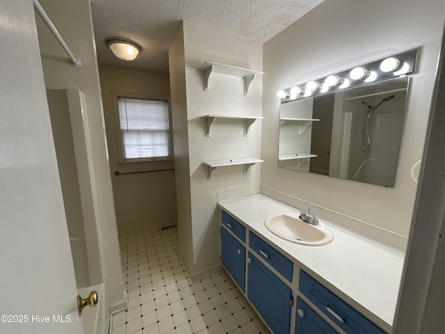 full bathroom with baseboards, tile patterned floors, a textured ceiling, vanity, and a shower