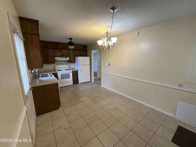 kitchen featuring white appliances, a sink, light countertops, under cabinet range hood, and a textured ceiling