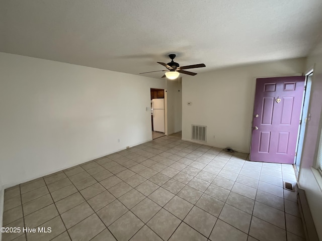 spare room featuring light tile patterned floors, a ceiling fan, visible vents, and a textured ceiling