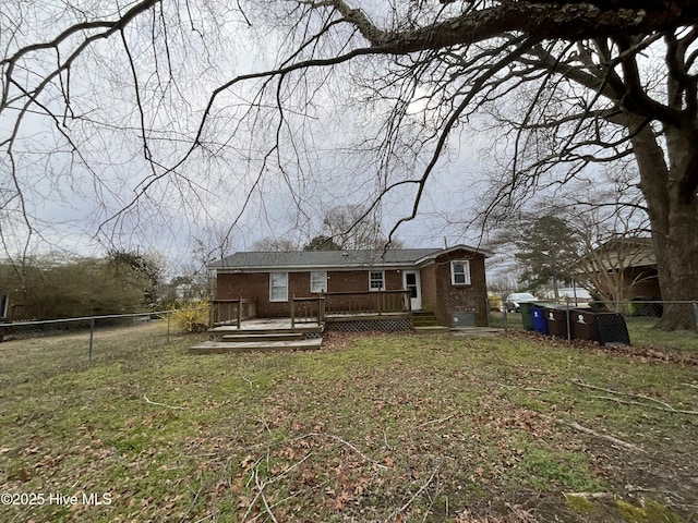 back of house with fence private yard, brick siding, a deck, and a yard