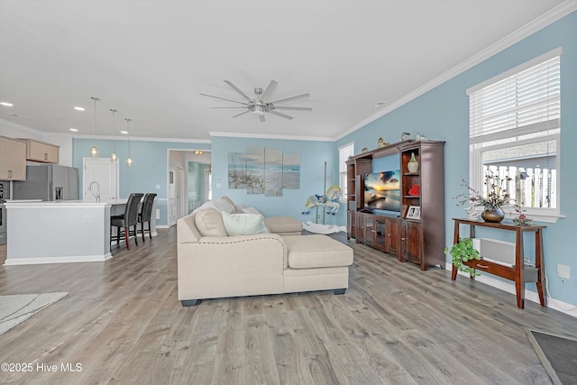 living area featuring light wood finished floors, crown molding, baseboards, ceiling fan, and recessed lighting