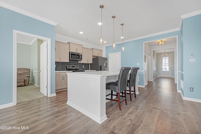 kitchen featuring backsplash, light wood-style flooring, stainless steel appliances, and an island with sink