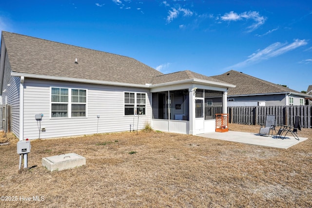 back of property with a sunroom, fence, roof with shingles, and a patio area