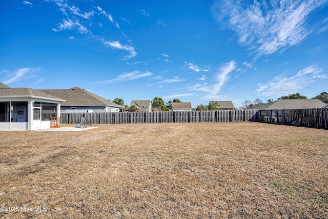 view of yard featuring a patio, a fenced backyard, and a sunroom