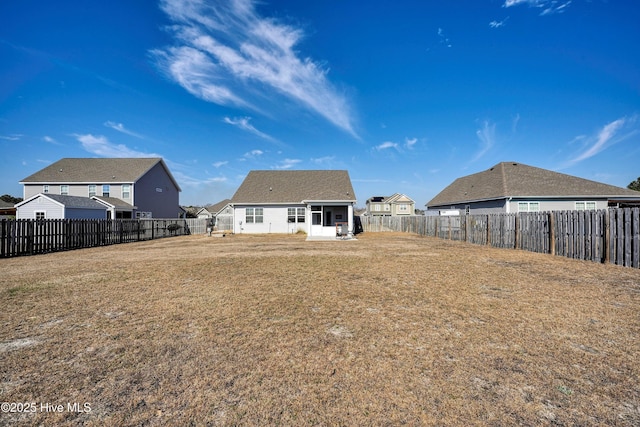 back of house with a lawn and a fenced backyard