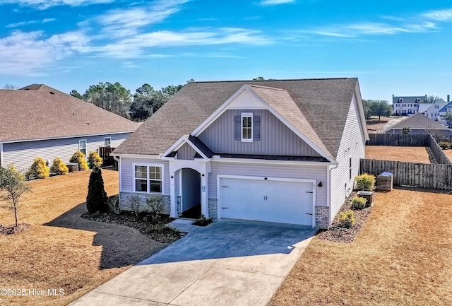 view of front facade with driveway, fence, board and batten siding, a front yard, and a shingled roof