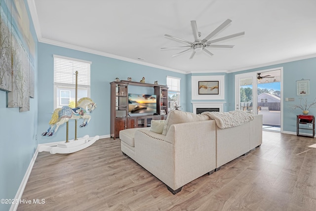 living room with light wood-type flooring, a healthy amount of sunlight, a fireplace, and crown molding