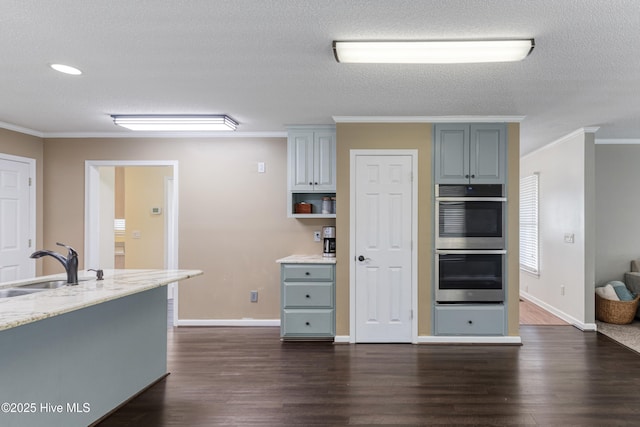 kitchen featuring a sink, double oven, crown molding, and dark wood-style floors