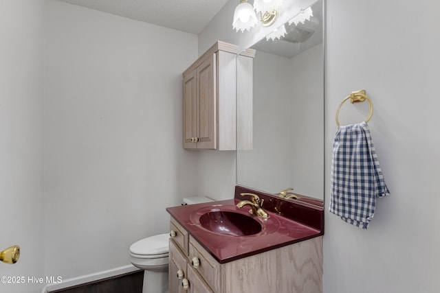 bathroom with toilet, vanity, and baseboards