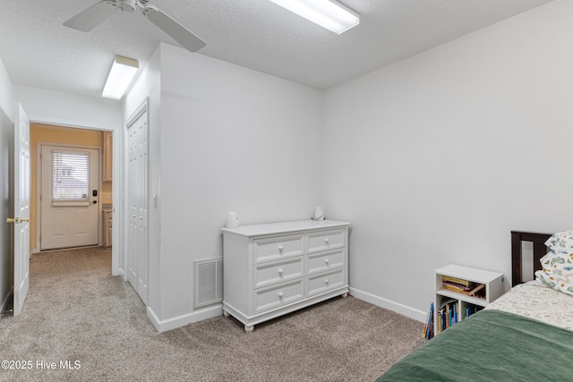 bedroom with baseboards, visible vents, light colored carpet, and a textured ceiling