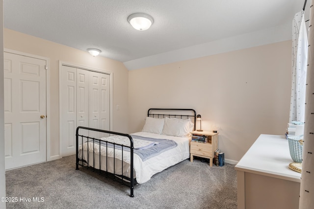 carpeted bedroom featuring a textured ceiling, a closet, baseboards, and vaulted ceiling