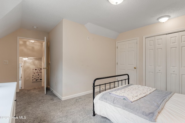 carpeted bedroom with a textured ceiling, a closet, baseboards, and vaulted ceiling