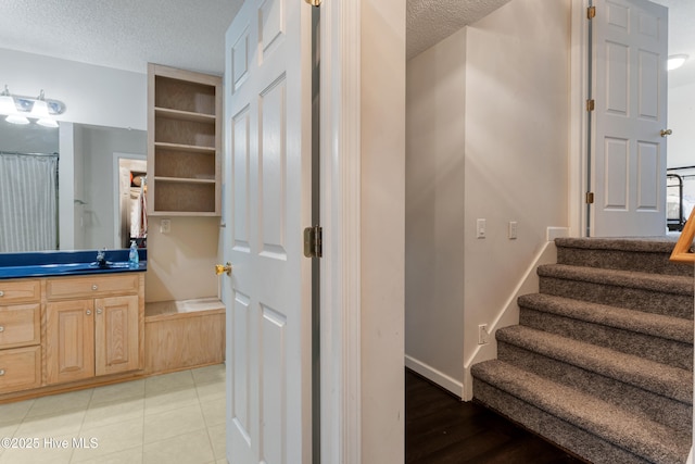 stairs featuring tile patterned floors, baseboards, and a textured ceiling