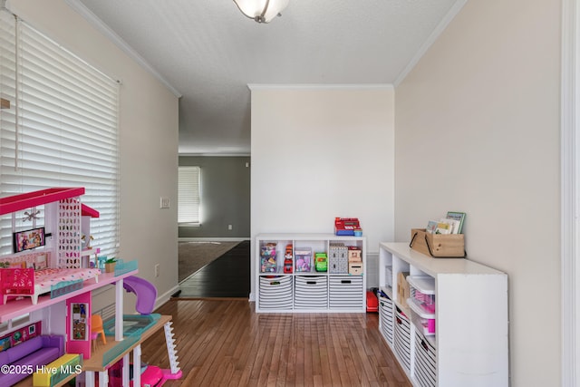 rec room with hardwood / wood-style floors, baseboards, ornamental molding, and a textured ceiling