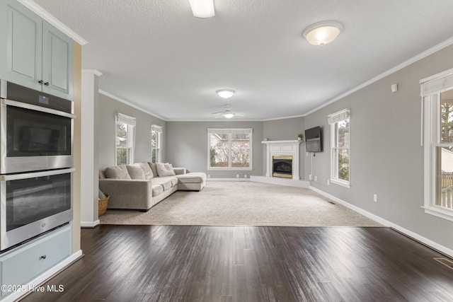 unfurnished living room featuring ceiling fan, a glass covered fireplace, and a wealth of natural light