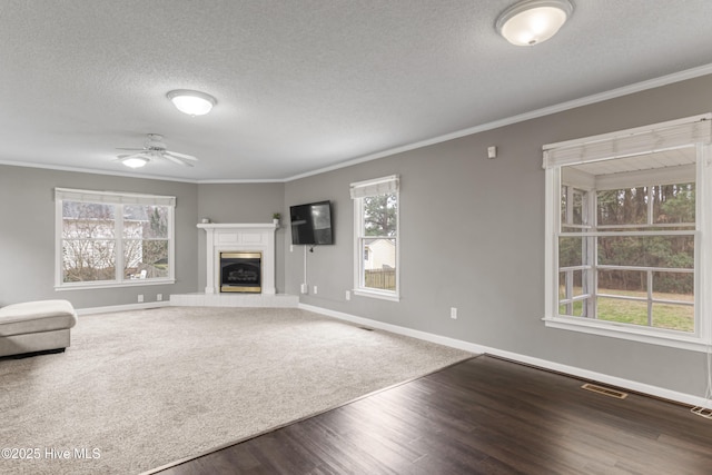 unfurnished living room with visible vents, baseboards, ornamental molding, ceiling fan, and wood finished floors