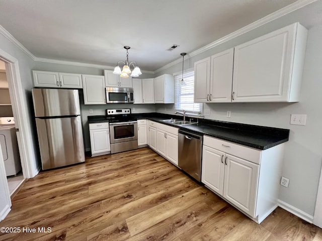 kitchen with washer / dryer, visible vents, appliances with stainless steel finishes, crown molding, and a sink