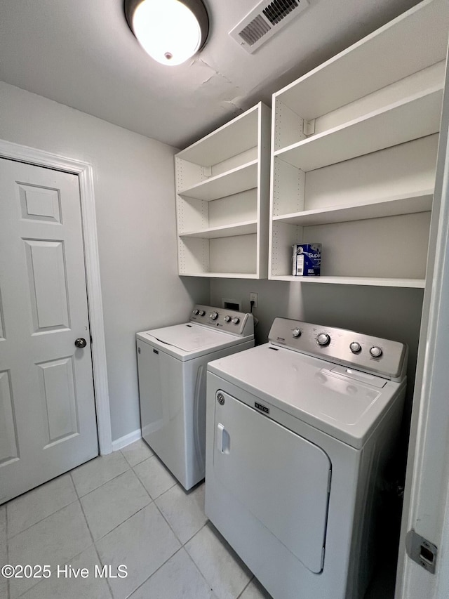 laundry area with laundry area, light tile patterned floors, baseboards, visible vents, and washer and clothes dryer