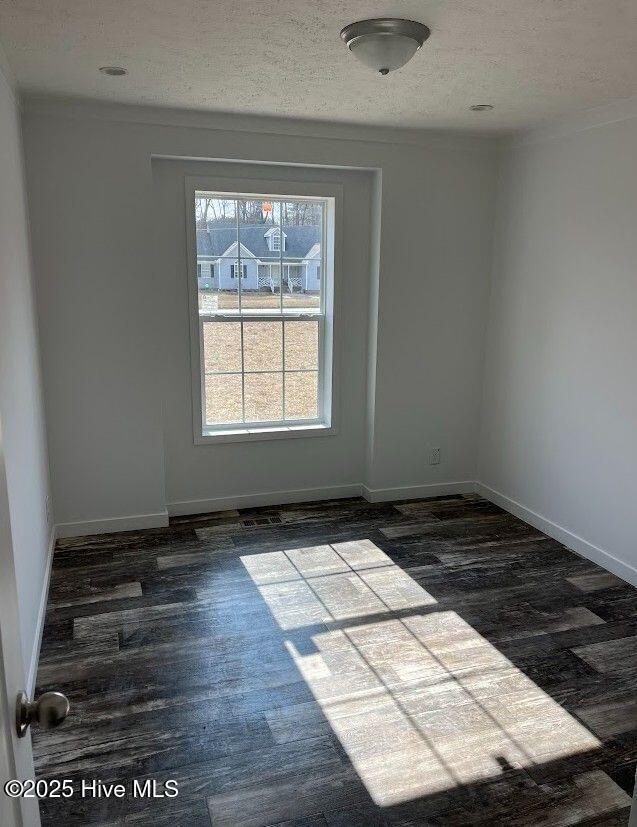 spare room featuring dark wood-style floors, baseboards, and a textured ceiling